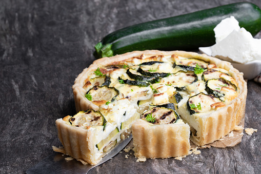 Homemade  courgette and feta quiche on rustic wooden table