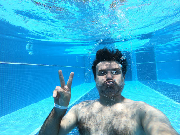 Happy men underwater in resort swimming pool