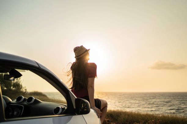 rückansicht einer frau, die in einem auto sitzt und die aussicht betrachtet - women long hair rear view beauty stock-fotos und bilder