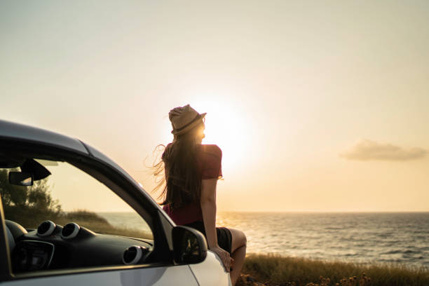 задний вид женщины, сидящей в машине, смотрящую на вид - travel vacations road highway стоковые фото и изображения