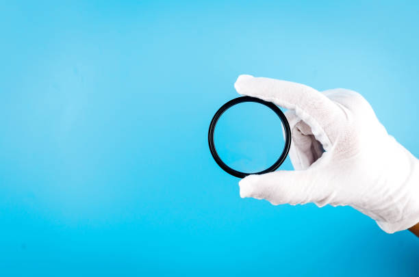 white gloved hand holding a camera lens - magnifying glass lens holding europe imagens e fotografias de stock