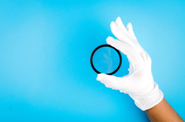 white gloved hand holding a camera lens - magnifying glass lens holding europe imagens e fotografias de stock