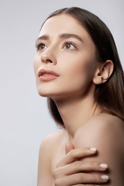 istock Beautiful young lady touching skin on her shoulder and looking away 1163030209