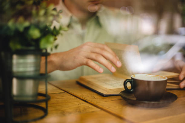 Unrecognizable man reading a book at a coffee shop
