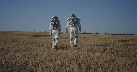 Long shot of two astronauts crossing a field