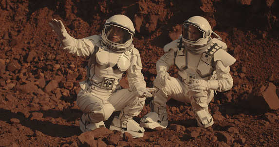 Medium shot of two astronauts collecting rock samples on Mars