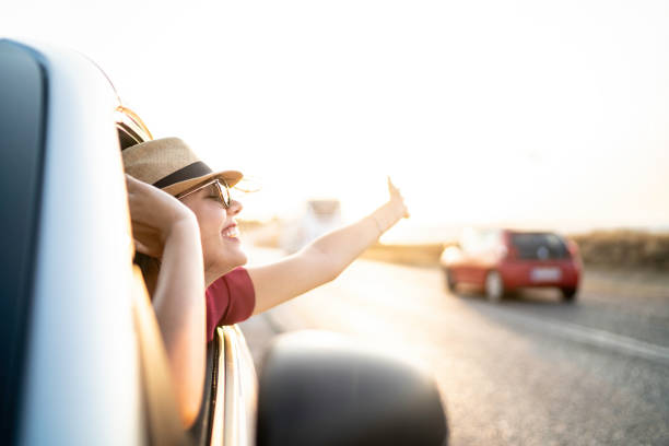 istock Woman leaning out car window with arms up 1163032425