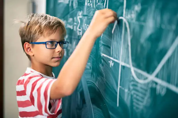 Photo of Little boy solving advanced mathematical problems