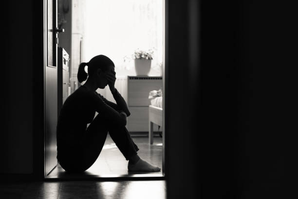 istock Sad young woman sitting on a floor at home 1163040304