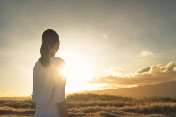 mujer de pie en la montaña mirando hacia la hermosa puesta de sol. - believe fotografías e imágenes de stock