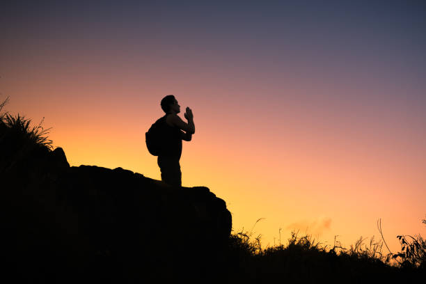 istock Man praying on the mountain top at sunset. 1163040369