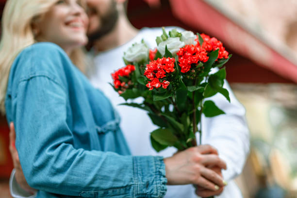 istock Pretty lady with bouquet smiling while standing near her boyfriend 1163040476