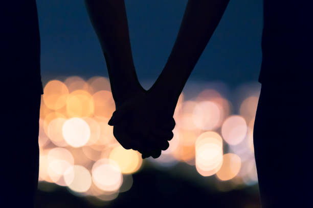 Couple holding hands Couple holding hands against city night lights. defocused woman stock pictures, royalty-free photos & images