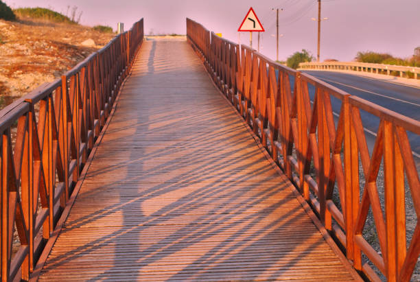 Empty wooden footbridge near an asphalt road on Limassol seafront during the sunset