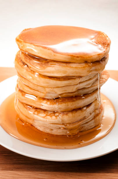 american pancake for breakfast, sweet snack and high calorie dessert concept with close up on flowing honey or maple syrup on a stack of thick pancakes isolated on rustic table with white background - pancake buttermilk buttermilk pancakes equipment imagens e fotografias de stock
