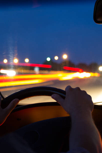 istock Car driving at night. View from inside the car. Mens hands on steering wheel. 1163049913