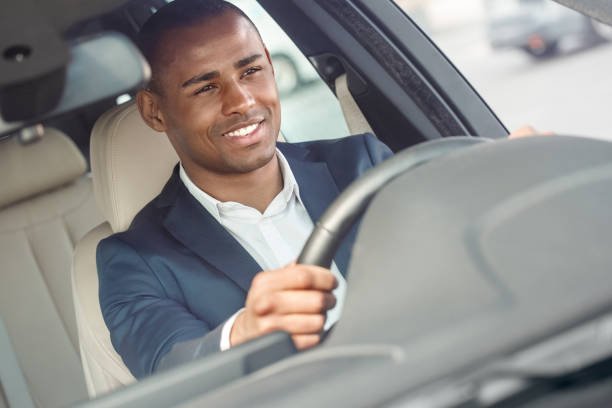 istock Young businessman driver sitting inside car holding steering wheel driving happy front outside view close-up 1163054922