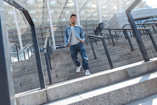 istock Outdoors Leisure.  guy walking down the stairs hands in pockets smiling joyful bottom view 1163060662