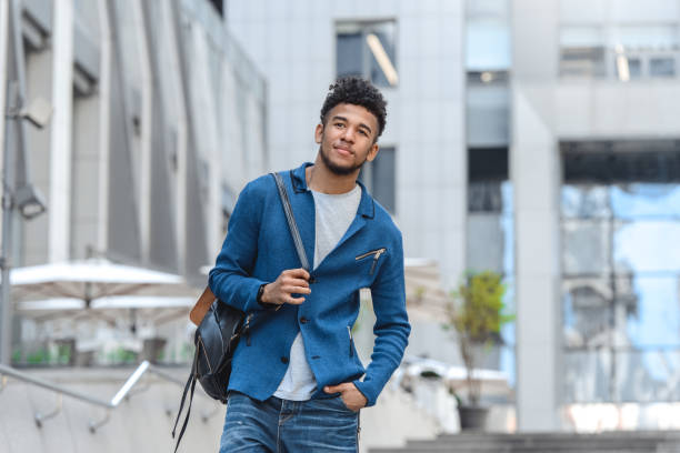 istock Smart Casual.  guy with backcpack standing on city street looking aside pensive 1163060671