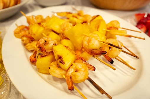 Close-up of white platter with shrimp and pineapple skewers, with grill marks, July 16, 2019