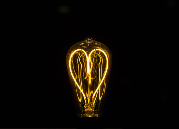 istock Lightbulb on dark background with bright wire in shape of a heart 1163065087