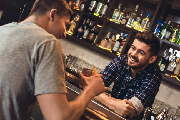istock Young bartender standing at bar counter with customer laughing joyful 1163065614
