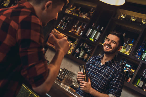 istock Young bartender standing at bar counter holding shaker talking with customer cheerful 1163065663