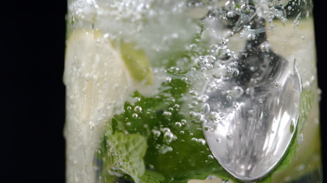 SLO MO Stirring a glass of a cold lime drink