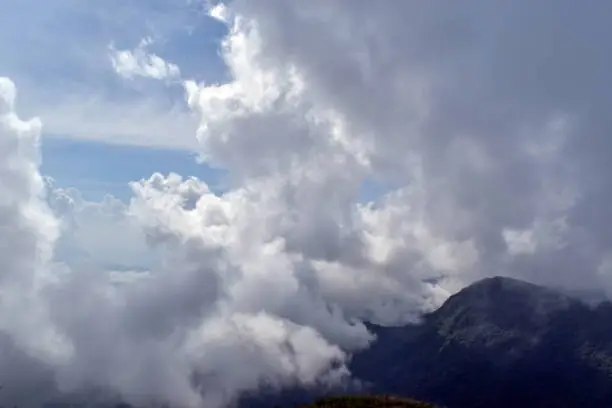 Photo of Mist-shrouded mountain peaks. Bright blinding sun. Blue sky. Fog. Mountains landscape. Highlands nature.