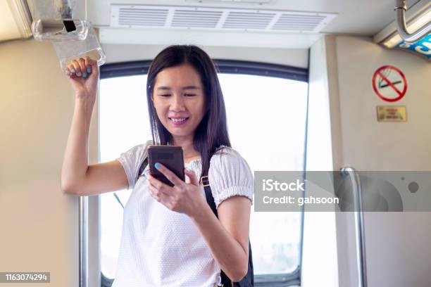 Woman Uses Mobile App While Riding Mrt Commuter Train Stock Photo - Download Image Now
