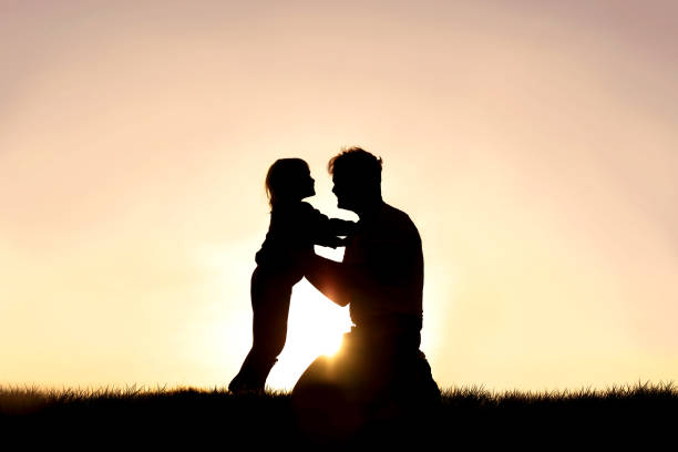 幸せな父と彼の小さな子供の笑顔と夕日で遊ぶシルエット - christin ストックフォトと画像