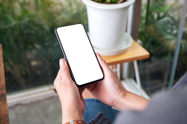 istock Mockup image of a woman holding and using black mobile phone with blank desktop screen in cafe 1163081086