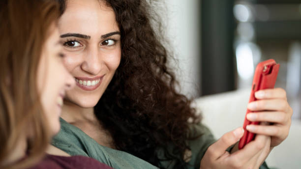 istock Young friends using mobile phone at home 1163082363