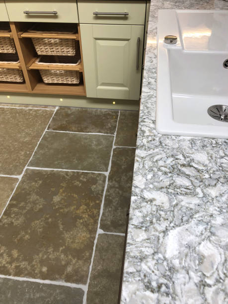 istock Image of luxury kitchen with grey and white marble granite worktop countertop surface above sliding wicker storage baskets for fruit and vegetables, by kitchen sink and drawers painted duck egg green, long chrome handles and stone floor tiles flooring 1163085634