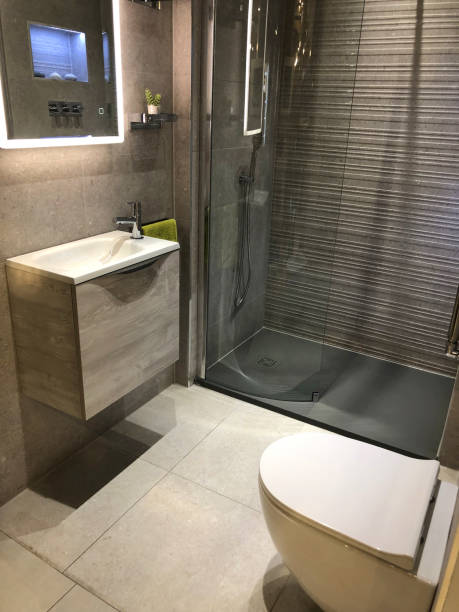istock Image of modern bathroom with large rectangular freestanding sink wash basin vanity unit under shaving mirror, separate shower cubicle behind sliding panelled glass door, white tiling tiles washroom wall, contemporary chrome shower hanging, wooden floor 1163087922