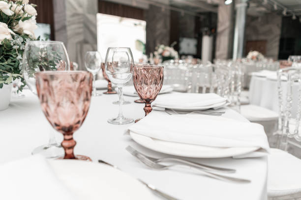 istock Wine glasses on round Banquet table served. Interior of restaurant for wedding dinner, ready for guests. Decorated with floral arrangement. Dishes, wine glasses and napkins. Catering concept. 1163092252