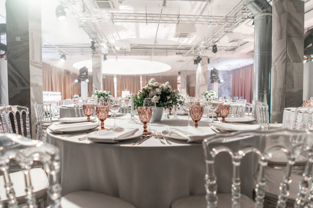 istock Round Banquet table served. Interior of restaurant for wedding dinner, ready for guests. Decorated with floral arrangement. Dishes, wine glasses and napkins. Catering concept. 1163092906