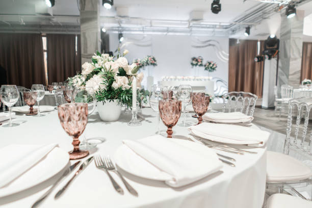 istock Interior of restaurant for wedding dinner, ready for guests. Round Banquet table served. Decorated with floral arrangement. Dishes, wine glasses and napkins. Catering concept. 1163092921