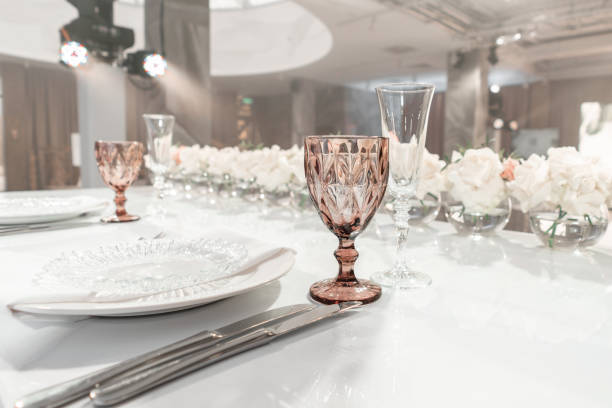 istock Wine glasses on round Banquet table served. Interior of restaurant for wedding dinner, ready for guests. Decorated with floral arrangement. Dishes, wine glasses and napkins. Catering concept. 1163093316