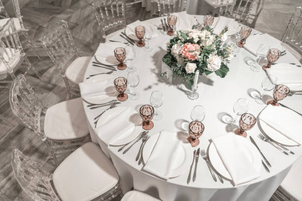 istock Round Banquet table served. Interior of restaurant for wedding dinner, ready for guests. Decorated with floral arrangement. Dishes, wine glasses and napkins. Catering concept. 1163093416