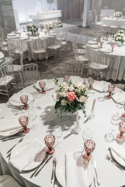 istock Wine glasses on round Banquet table served. Interior of restaurant for wedding dinner, ready for guests. Decorated with floral arrangement. Dishes, wine glasses and napkins. Catering concept. 1163093528
