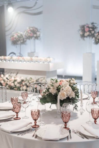 istock Wine glasses on round Banquet table served. Interior of restaurant for wedding dinner, ready for guests. Decorated with floral arrangement. Dishes, wine glasses and napkins. Catering concept. 1163094057