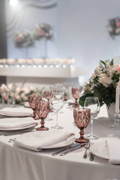 istock Wine glasses on round Banquet table served. Interior of restaurant for wedding dinner, ready for guests. Decorated with floral arrangement. Dishes, wine glasses and napkins. Catering concept. 1163094071