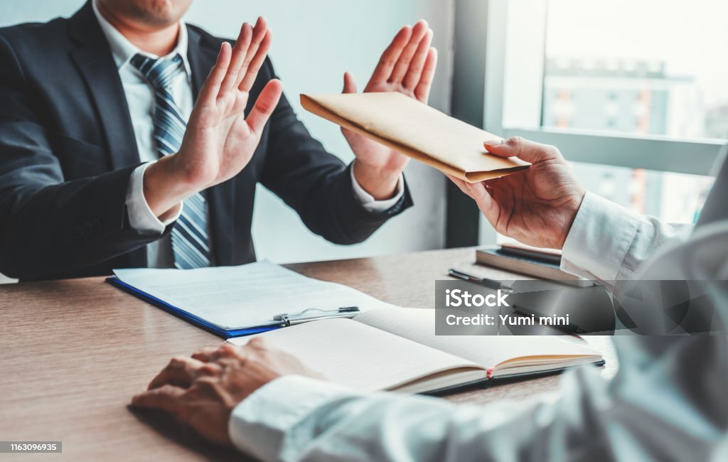 Corruption and Bribery,Businessman manager refusing receive money from Business man passing money dollar bills to deal contract Bribing Stock Photo