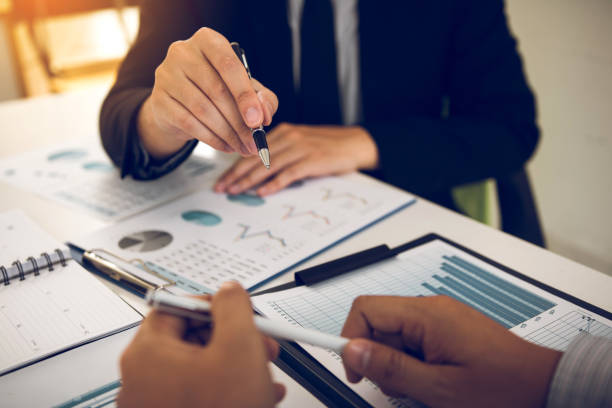 istock Two business partnership coworkers analysis cost work progress and gesturing with discussing a financial planning graph and company financial during a budget meeting in office room. 1163104111