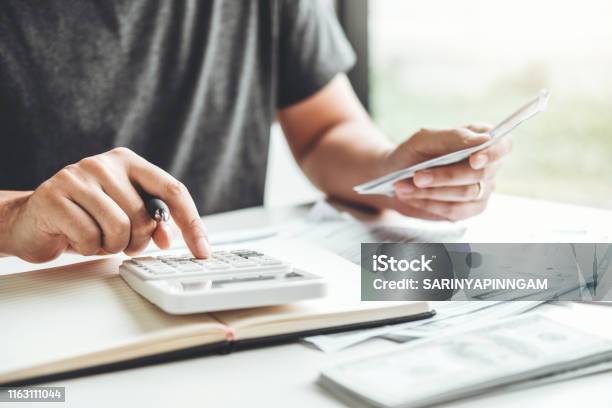 Man Using Calculator Accounting Calculating Cost Economic Bills With Money Stack Step Growing Growth Saving Money In Home Finance Concept Stock Photo - Download Image Now
