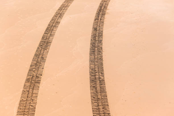 Vehicle machine tracks imprint on beach sand though the frame overhead photo.