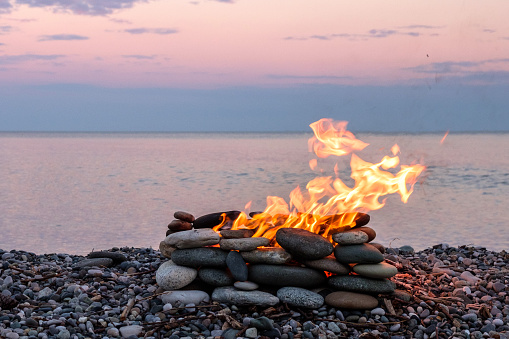a fire burning in the stone place, beach and sea background