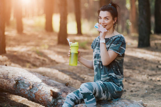 istock woman drinks amino acids and has a protein bar in the forest 1163124123