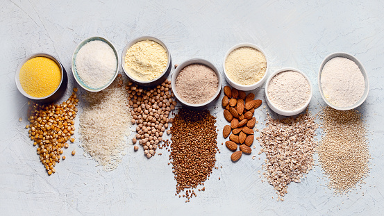 Various gluten free flour - chickpeas, rice, buckwheat, quinoa, almond, corn, oatmeal on grey background.
